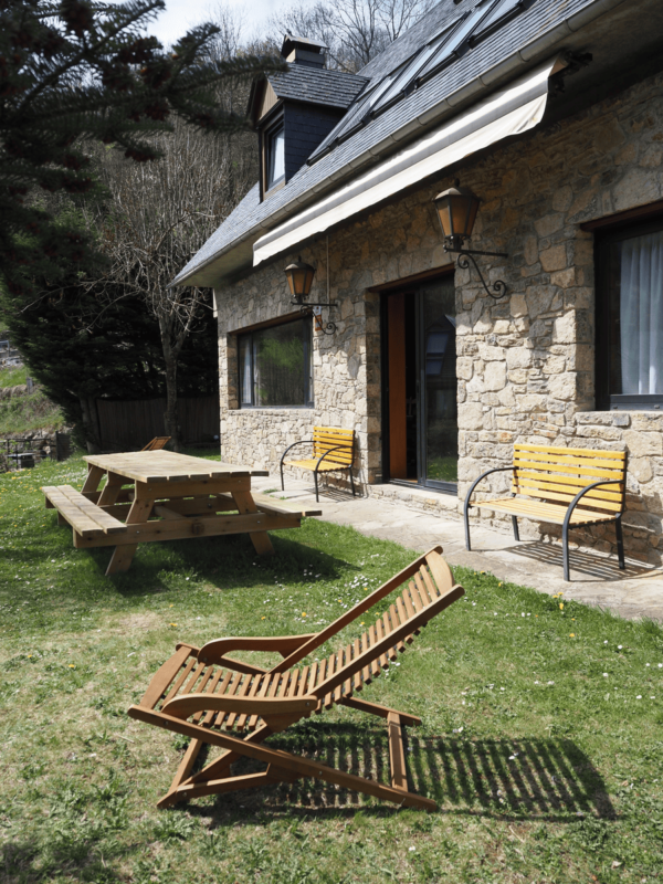Mesa de picnic de madera y hamaca en el jardín soleado de Casa Lola Pirene, ideal para grupos de 12.