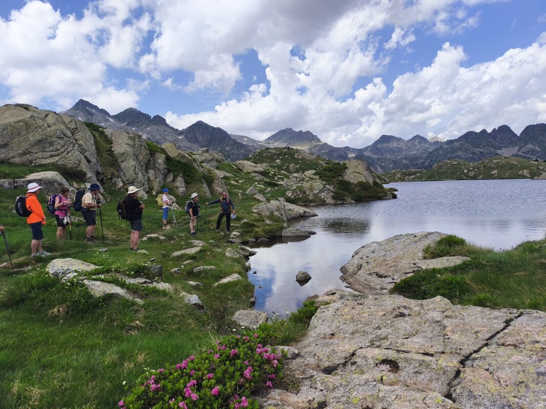 Grupo de familias haciendo senderismo junto a un lago en vacaciones en la Val d Aran